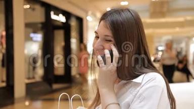 女孩坐在长凳上用商场里的电话